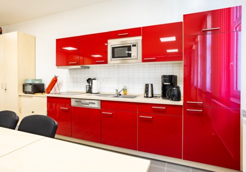 Küchenzeile in Rot mit Küchengeräten und Tisch im Vordergrund