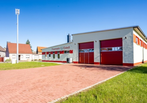 Blick auf das Gerätehaus der Feuerwehr Estedt mit zwei großen roten Toren