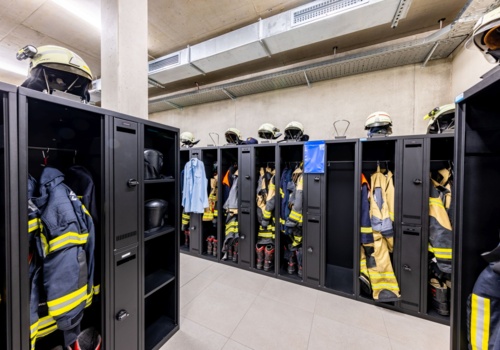 Ausrüstung von Feuerwehrleuten hängt in schwarzen Einsatzspinden