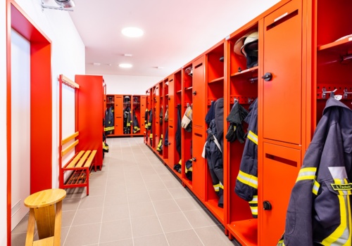 Einsatzkleidung der Feuerwehr hängt in roten Feuerwehrspinden