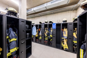 Ausrüstung von Feuerwehrleuten hängt in schwarzen Einsatzspinden